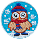 A brown owl stares wide-eyed ahead. It is dressed in a warm toque, scarf, and boots as it stands amongst falling snowflakes.