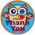 An owl raises its wings in the air, winks, and kisses a heart towards the viewer. The text Thank You is at the bottom of this round crest.