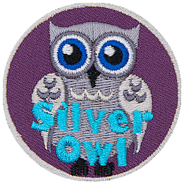 A silver-coloured owl with blue eyes. The words Silver Owl are stitched in blue on the bottom.