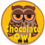 A brown owl with dark brown wings and half-lidded orange eyes. The words Chocolate Owl are at the bottom.