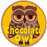 A brown owl with dark brown wings and half-lidded orange eyes. The words Chocolate Owl are at the bottom.