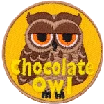 A brown owl with dark brown wings and half-lidded orange eyes. The words Chocolate Owl are at the bottom.