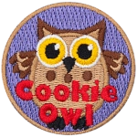A fat brown owl with wide yellow eyes. The words Cookie Owl are stitched below.