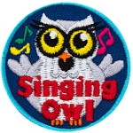 A chubby white owl with yellow eyes and eyelashes. The words Singing Owl are at the bottom.