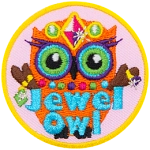 An orange owl wearing a crow, necklace and rings. The words Jewel Owl are across the bottom.