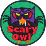 A black owl with a purple mask and red eyes. The beak has fangs. The words Scary Owl are across the bottom.