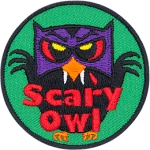 A black owl with a purple mask and red eyes. The beak has fangs. The words Scary Owl are across the bottom.
