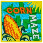 The words Corn Maze are on two arrows. An ear of corn is in the foreground.