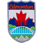 This emblem has the name Edmonton at the top on a blue background. In the section below, the name is Edmonton's famous landmarks. From bottom to top are the three pyramids of the Muttart Conservatory, the Waterdale Bridge, the North Saskatchewan River, and downtown Edmonton (including the Legislature Building). The background is a red maple leaf on a white backing.