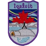 Iqaluit is stitched above St. Jude's Cathedral with Frobisher Bay and mountains in the background. A red maple leaf is in the sky in front of the northern lights.