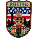 The word Austin is above the parliament building in Austin. The flag of the USA is in the background.