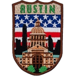 The word Austin is above the parliament building in Austin. The flag of the USA is in the background.