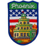 The word Phoenix is above a tiered building in a desert. The flag of the USA is in the background.