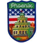 The word Phoenix is above a tiered building in a desert. The flag of the USA is in the background.