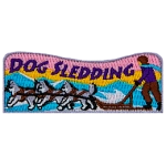 The words Dog Sledding are above a dog sled pulled by three dogs.
