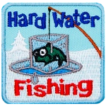 A fish frozen in an iceblock is pulled out of an ice fishing hole. The words Hard Water Fishing are above and below.