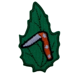 A folding knife is partially open on a green leaf.