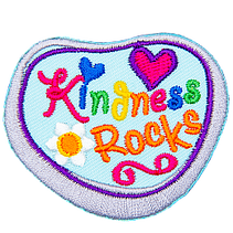 A grey rock has been painted with blue paint and the words Kindness Rocks.