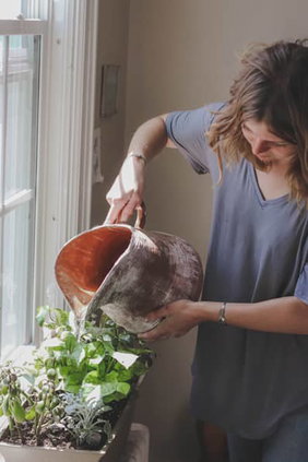 Someone watering a windowsill plant box.